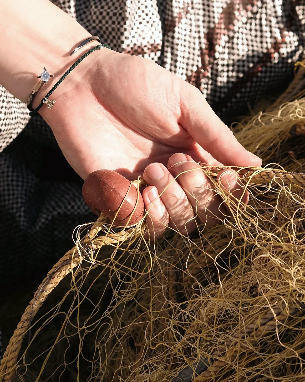 Bracelet on wrist resting on a fishing net