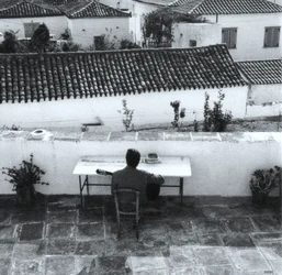 Writer at a table on a Hydra terrace, archival black and white