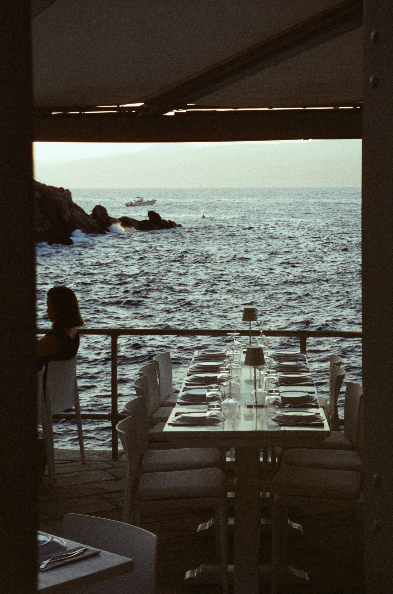 A long dinner table set above the sea at dusk, Hydra