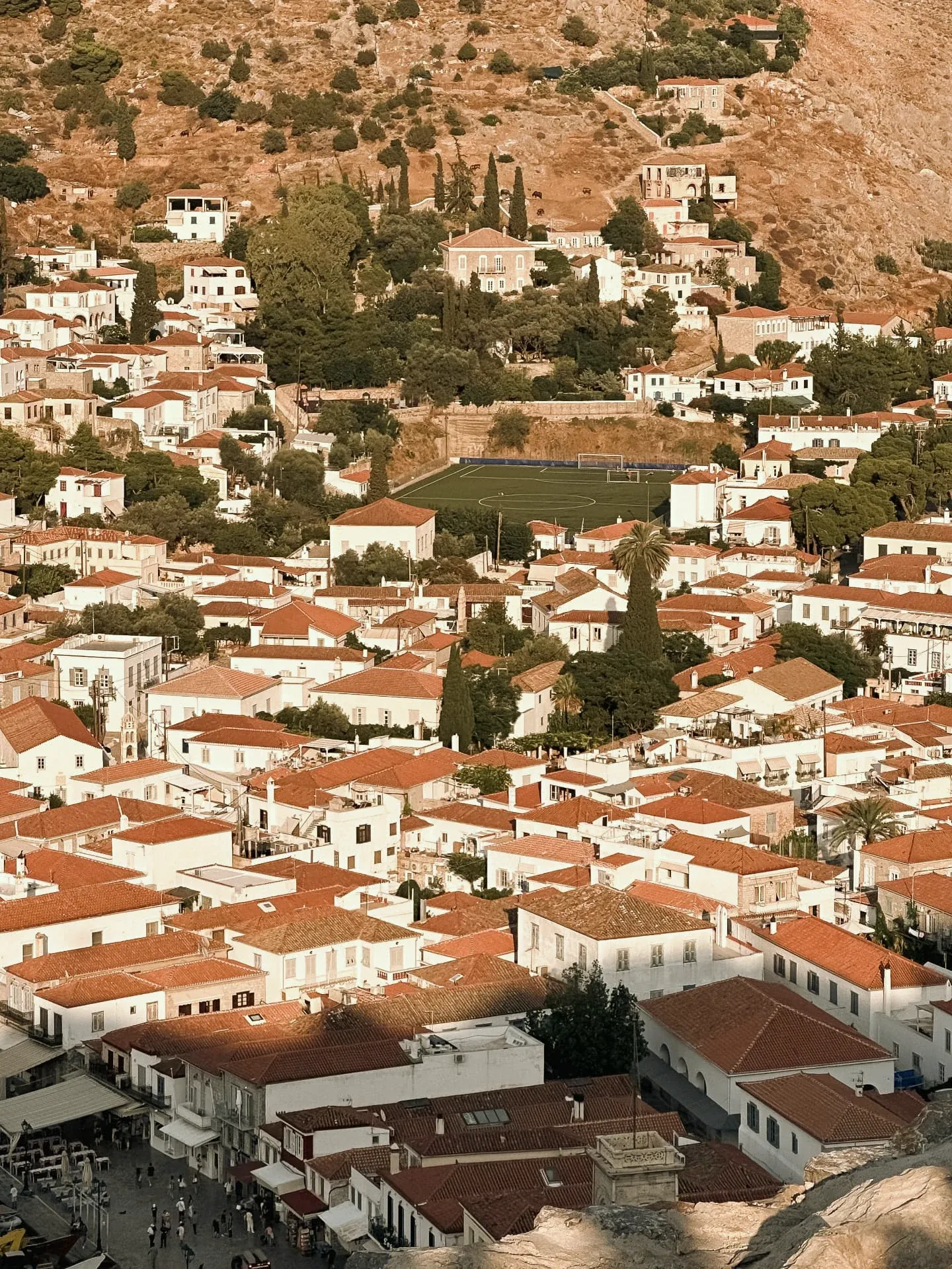 Hydra town seen from the hillside, terracotta roofs in evening light
