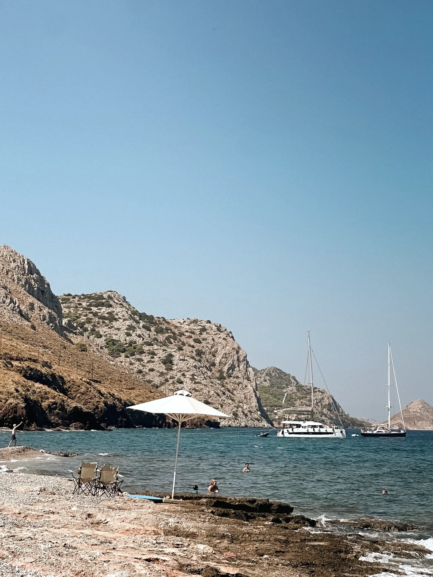 Morning swim at a quiet Hydra cove, boats at anchor