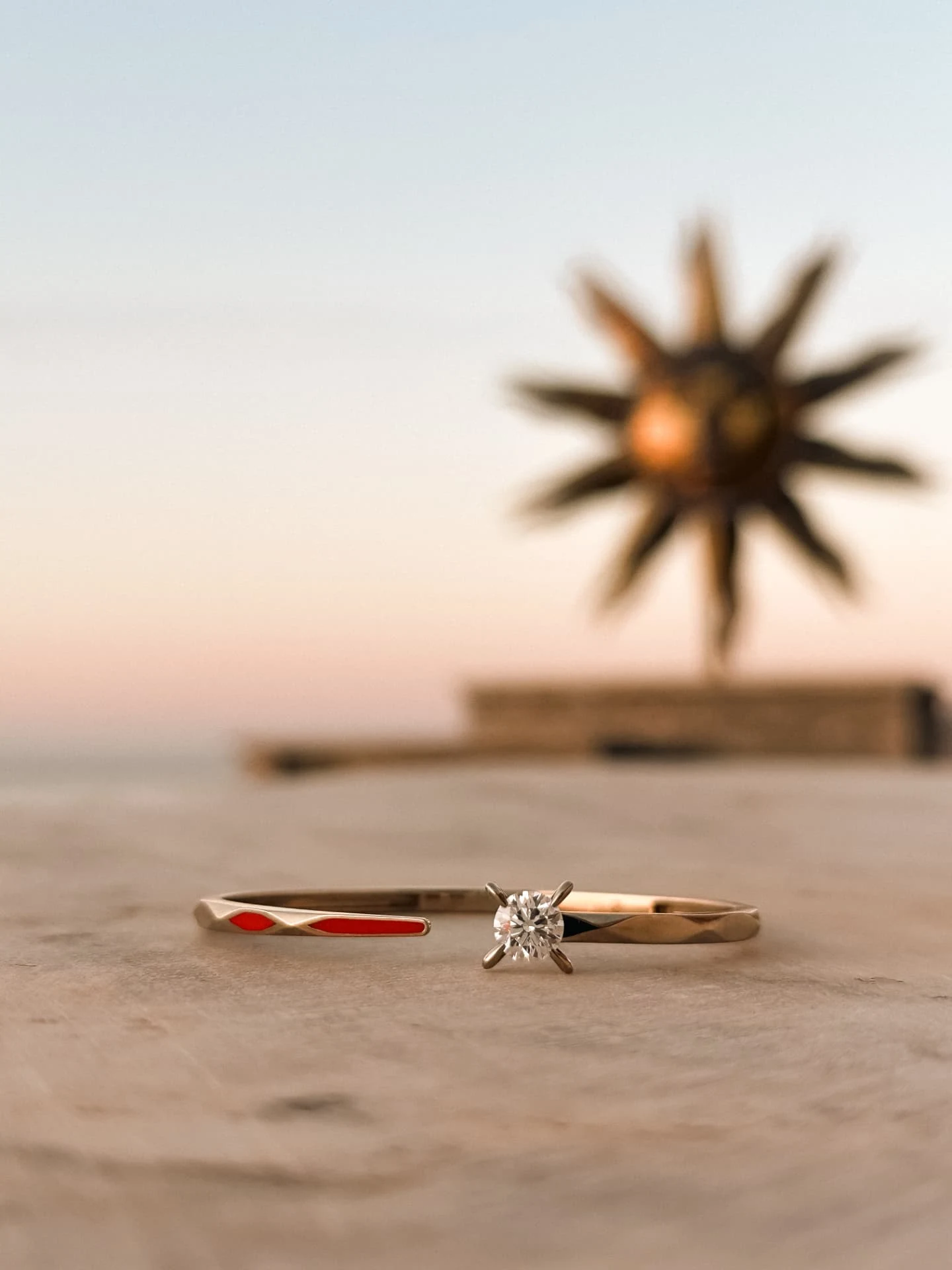 Ring and enamel band with Hydra sun sculpture at dusk