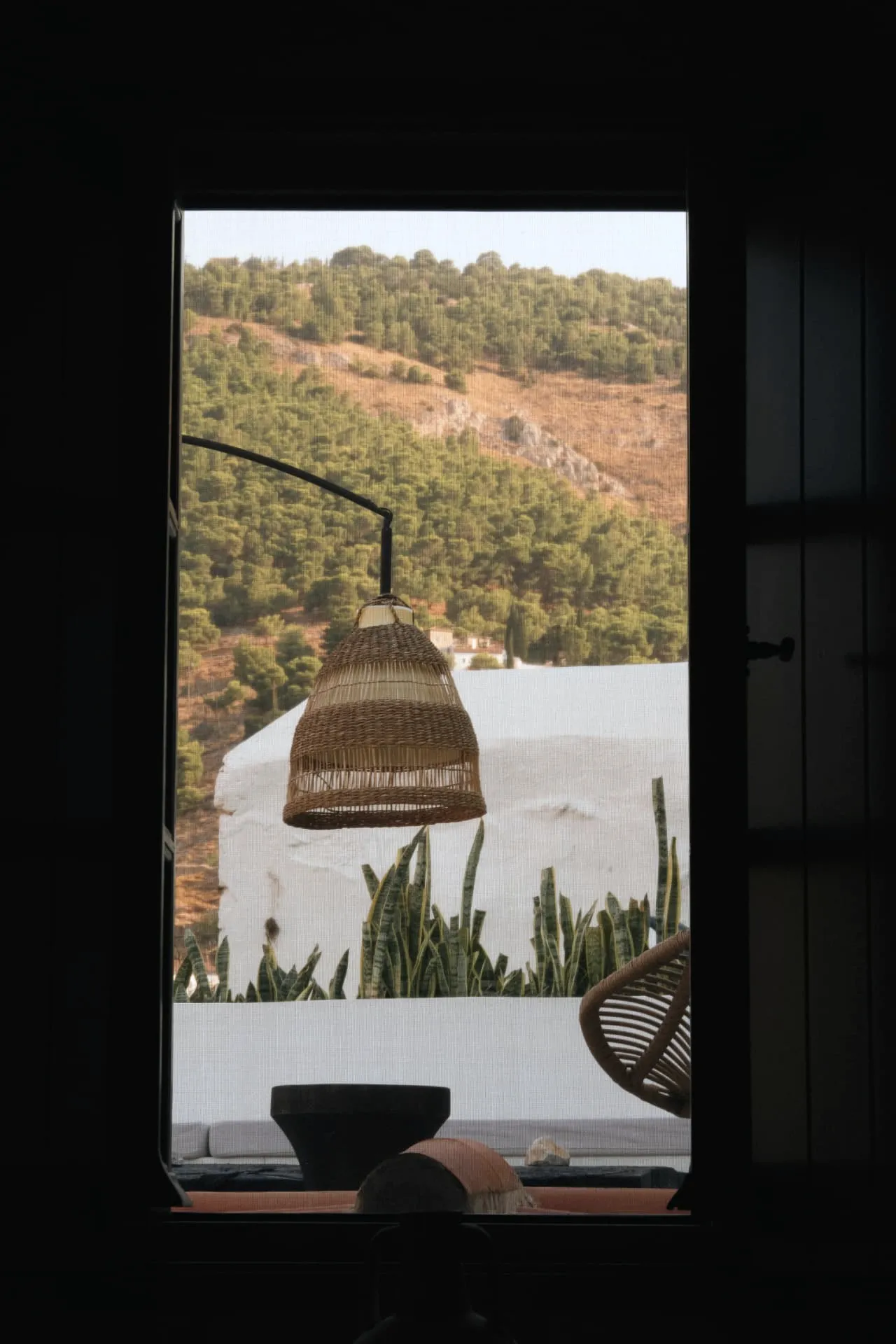Rattan lamp in a dark window looking out over the Hydra hillside